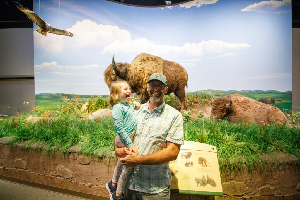 Bryan with young child standing in front of a Bison installation at an Oklahoma museum.