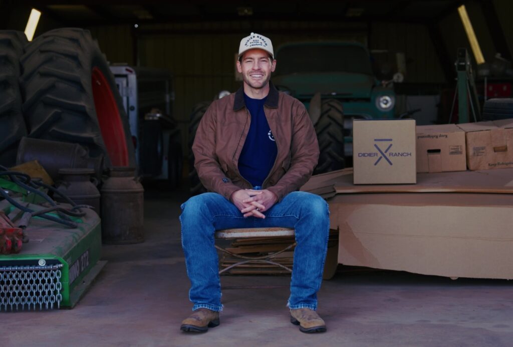 Gatlin sitting in front of his barn smiling.