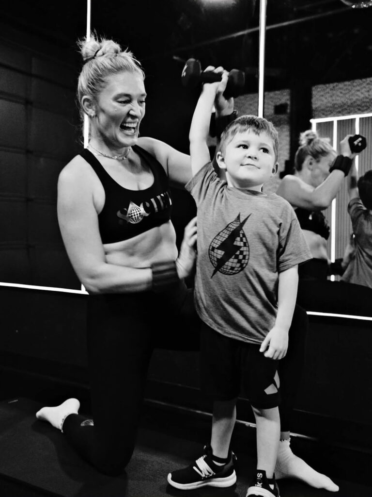 Alli Cooper's young son impresses her as he lifts weights at the Sweat Society, a cycle and fitness studio she founded after moving back to Oklahoma