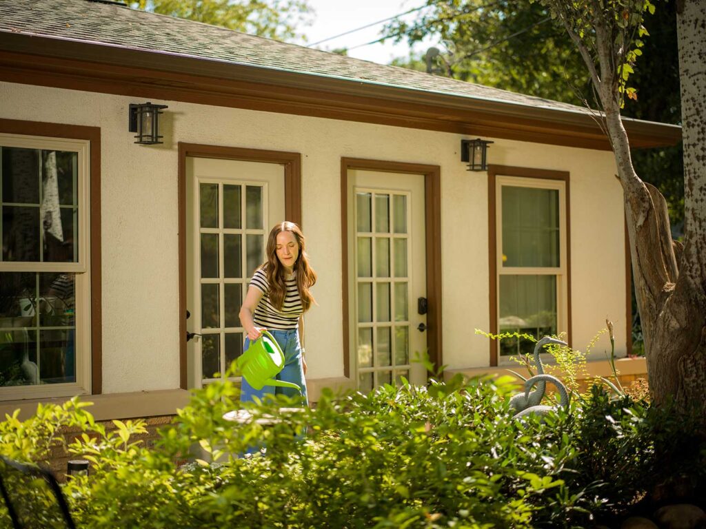 A homeowner waters her plants in the flowerbed at her home in Oklahoma