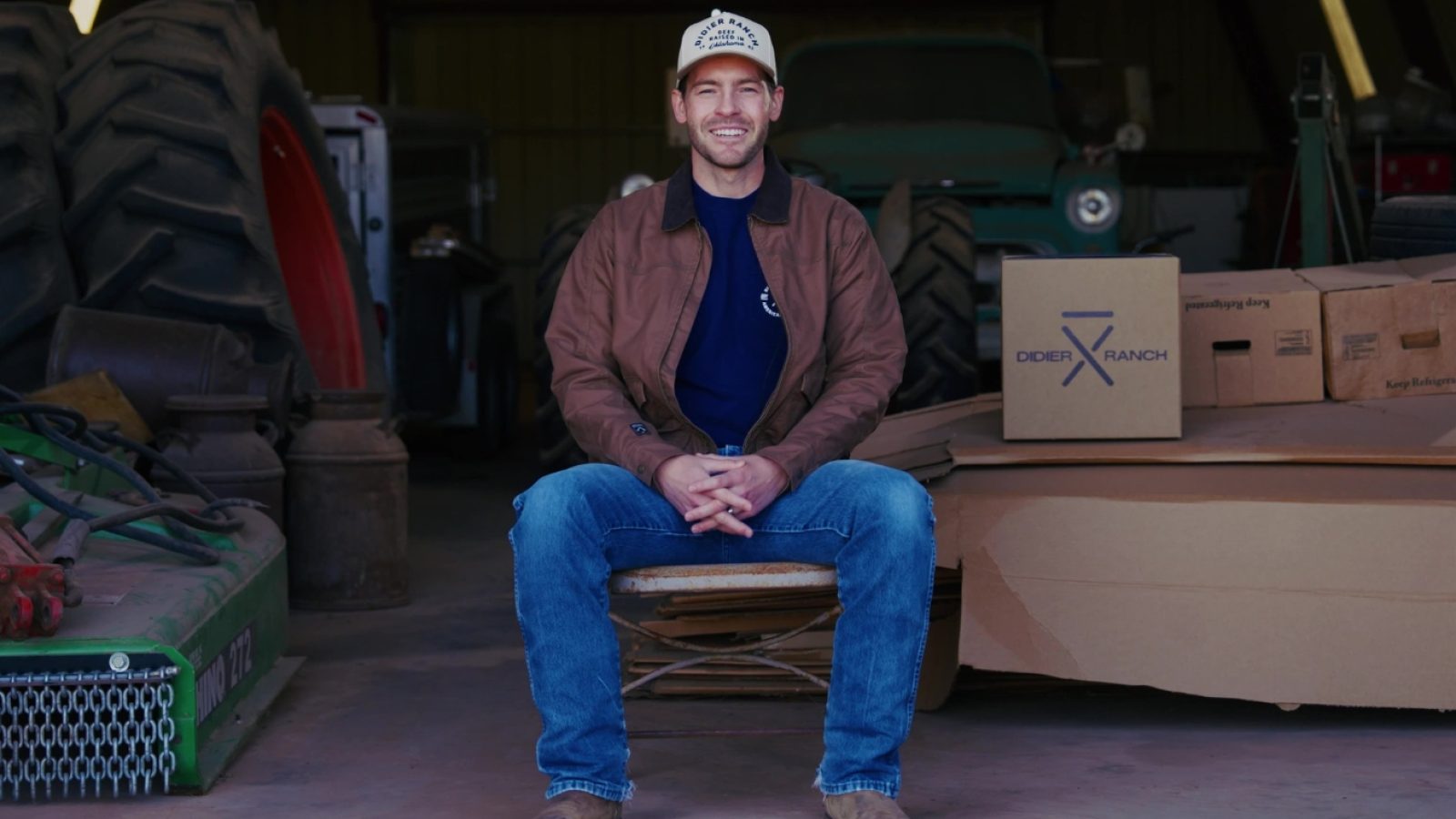 Gatlin sitting in front of his barn smiling.